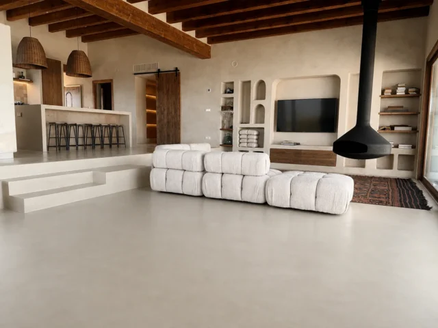 Salón con revestimiento de cal, chimenea suspendida y vigas de madera