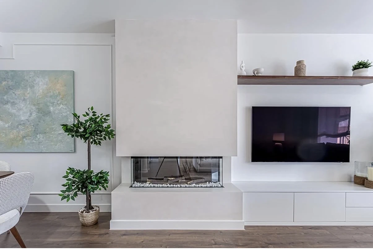 Revestimientos decorativos a medida en salón con chimenea blanca y mobiliario integrado